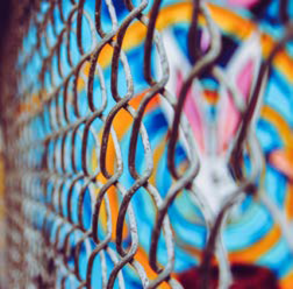 Stedelijk hekwerk met kleurrijke graffiti, urban sfeer.